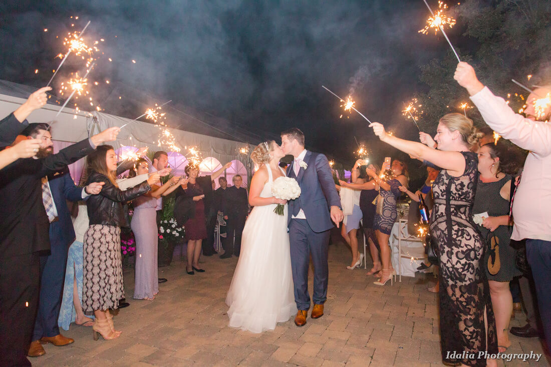 couple kissing while guests holds sparklers