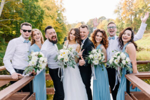 Positive, stylish guests at the wedding together with the couple in love laugh and pose on the camera